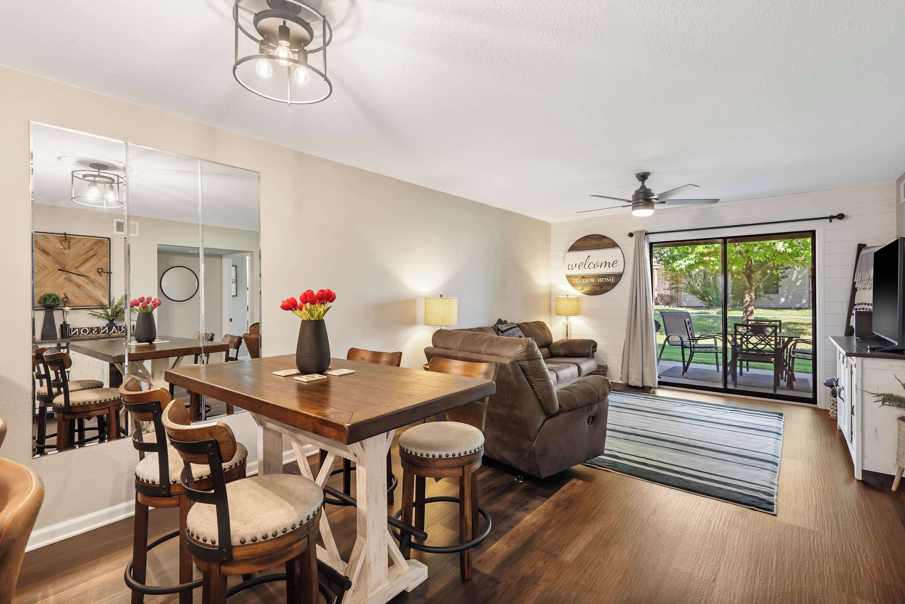 A modern living room with a dining area, a sofa, and a ceiling fan.