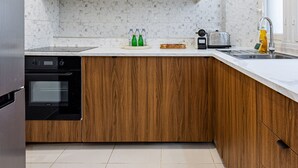 A modern kitchen with white cabinets, a wooden countertop, and a stainless steel sink. - 3 Chambres - Paris 17 - 6personnes - Renové (Paris)