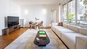A modern living room with a TV, sofa, dining table, and chairs. - 3 Chambres - Paris 17 - 6personnes - Renové (Paris)