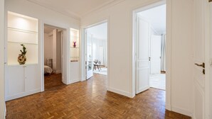 A spacious hallway with wooden flooring, white walls, and multiple doorways leading to different rooms. - 3 Chambres - Paris 17 - 6personnes - Renové (Paris)