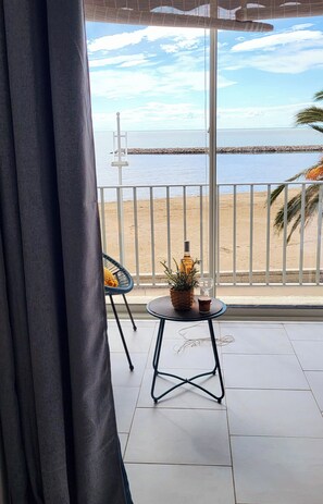 Un balcón con vistas a la playa, una planta en maceta y una silla.