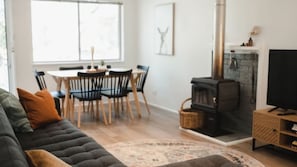 Ein Wohnzimmer mit einer Couch, einem Fernseher, einem Kamin und einem Essbereich mit Stühlen und einem Tisch.