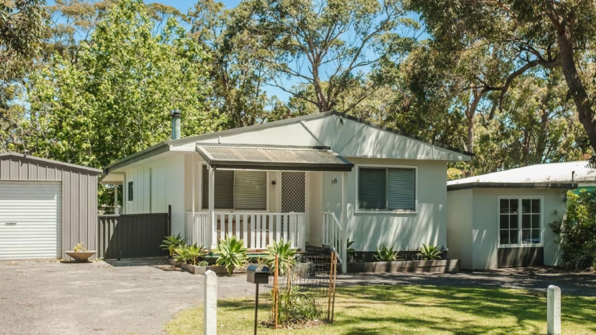 A single-story house with a front porch, a garage, and a small garden area.
