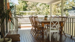 Eine Holzterrasse mit Tisch und Stühlen, umgeben von einem weißen Geländer.