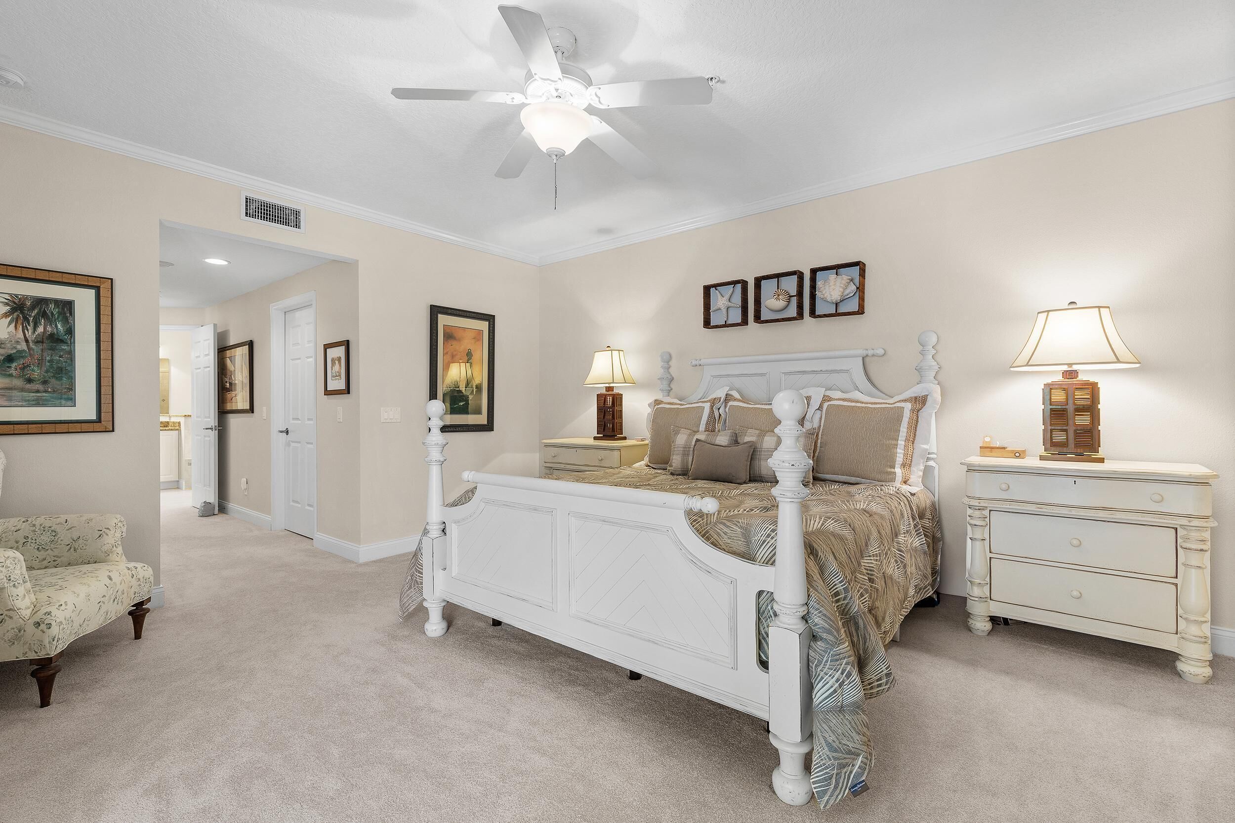 A bedroom with a four-poster bed, a nightstand, a chair, and a ceiling fan.