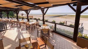 Un patio al aire libre con mesas y sillas, con vista a una playa.