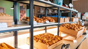 Mostrador de panadería con diversas opciones horneadas, incluyendo pasteles y pan, dispuestas en estantes y cajas de madera.