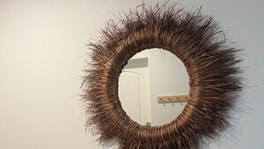Un meuble-lavabo de salle de bain avec un miroir rond, une petite étagère avec des livres et des objets décoratifs, et un plancher en bois.