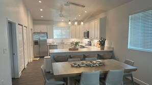 Une cuisine moderne avec des meubles blancs, un îlot central et un coin repas avec des chaises blanches.