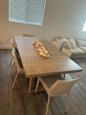 A dining area with a wooden table, white chairs, and a wooden chain centerpiece. - Spacious, Completely Renovated 3BR Keys Getaway By John Pennekamp & Restaurants (Key Largo)