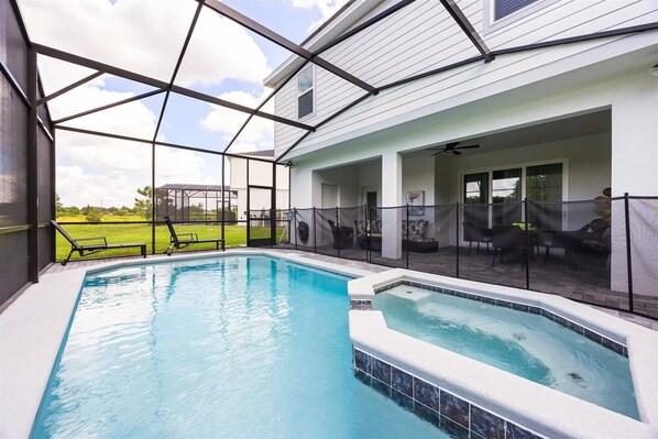 An indoor swimming pool with a glass ceiling, surrounded by lounge chairs and a patio area.