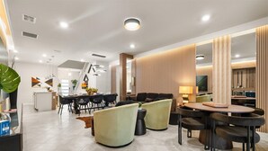 Un salon moderne avec un coin repas, comprenant un canapé, des fauteuils, une table basse et un téléviseur.
