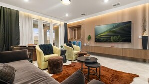 Un salon moderne doté d’un grand téléviseur à écran plat, de sièges confortables et d’un mur décoratif en bois.