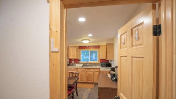 Un pasillo estrecho que conduce a una cocina con armarios de madera y un comedor.