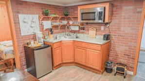 A compact kitchen with wooden cabinets, a built-in microwave, and a small refrigerator.