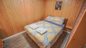 A small, single-bed room with wooden walls and a wooden floor.