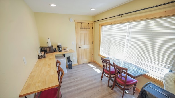 A compact kitchen with a wooden table, chairs, a microwave, and a coffee maker.