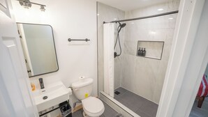 Une salle de bain moderne équipée de toilettes, d’un lavabo et d’une douche à parois de verre.