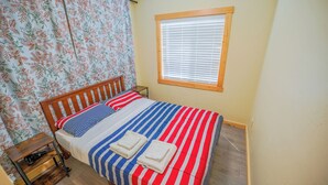 A neatly made bed with striped bedding, a wooden headboard, and two folded towels.