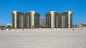 A beachfront hotel with a symmetrical design, multiple floors, and a central entrance.