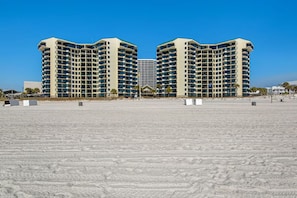 A beachfront hotel with a symmetrical design, multiple floors, and a central entrance.