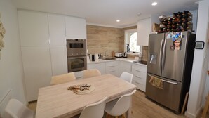 Une cuisine moderne avec des meubles blancs, des appareils en acier inoxydable et un meuble à bouteilles.