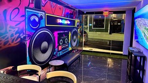 A modern interior with a DJ booth, seating area, and a large TV screen.