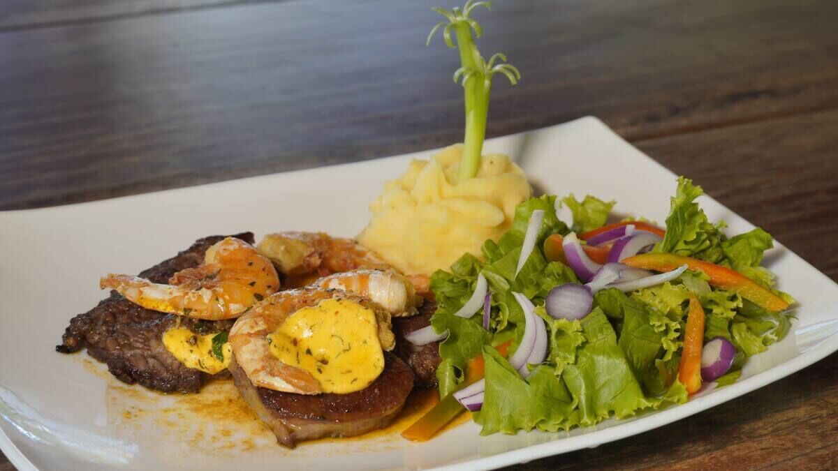 Een bord met steak, gepureerde aardappelen en een salade.
