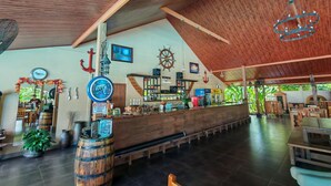 Un espacio amplio tipo bar, con vigas de madera, una barra y diversos utensilios.