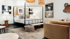 Une chambre à coucher moderne avec un lit à baldaquin, une table ronde en bois et un canapé beige.