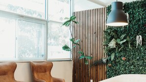Un espace de bureau moderne avec deux fauteuils en cuir marron, une table basse en béton et un mur végétal.