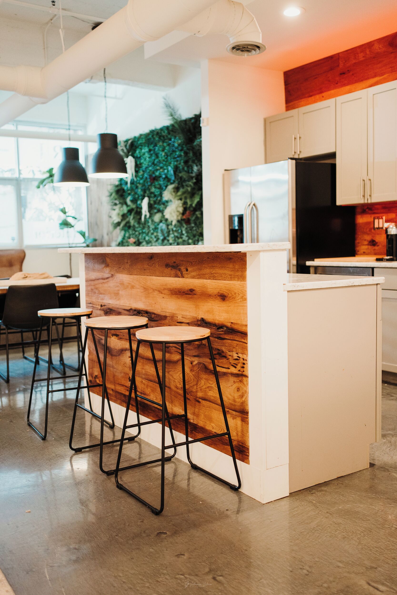 Une cuisine moderne avec un îlot central en bois, des tabourets de bar et des armoires blanches.
