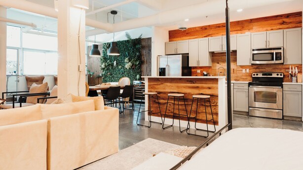 Une cuisine moderne dotée d’appareils électroménagers en acier inoxydable, d’un mur d’accent en bois et d’un coin bar avec des tabourets.