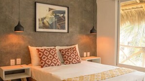 Quarto com cama de madeira, almofadas estampadas, um quadro na parede e uma mesa de cabeceira.