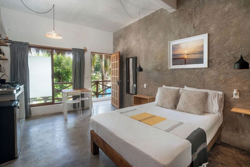 Un dormitorio con cama, escritorio y vistas al exterior.