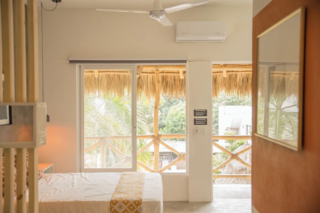 A bedroom with a bed, a ceiling fan, and a window with a view of palm trees.