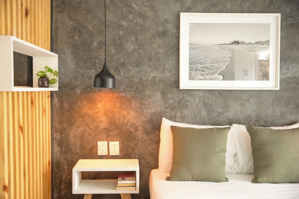 Une chambre à coucher avec un lit, une table de chevet avec une lampe, une étagère avec une plante et un tableau encadré au mur.