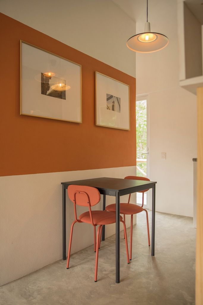 Un comedor con una mesa y sillas, una obra de arte enmarcada en la pared y una lámpara colgante.