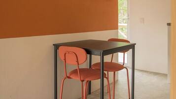 Un comedor con una mesa y sillas, una obra de arte enmarcada en la pared y una lámpara colgante.
