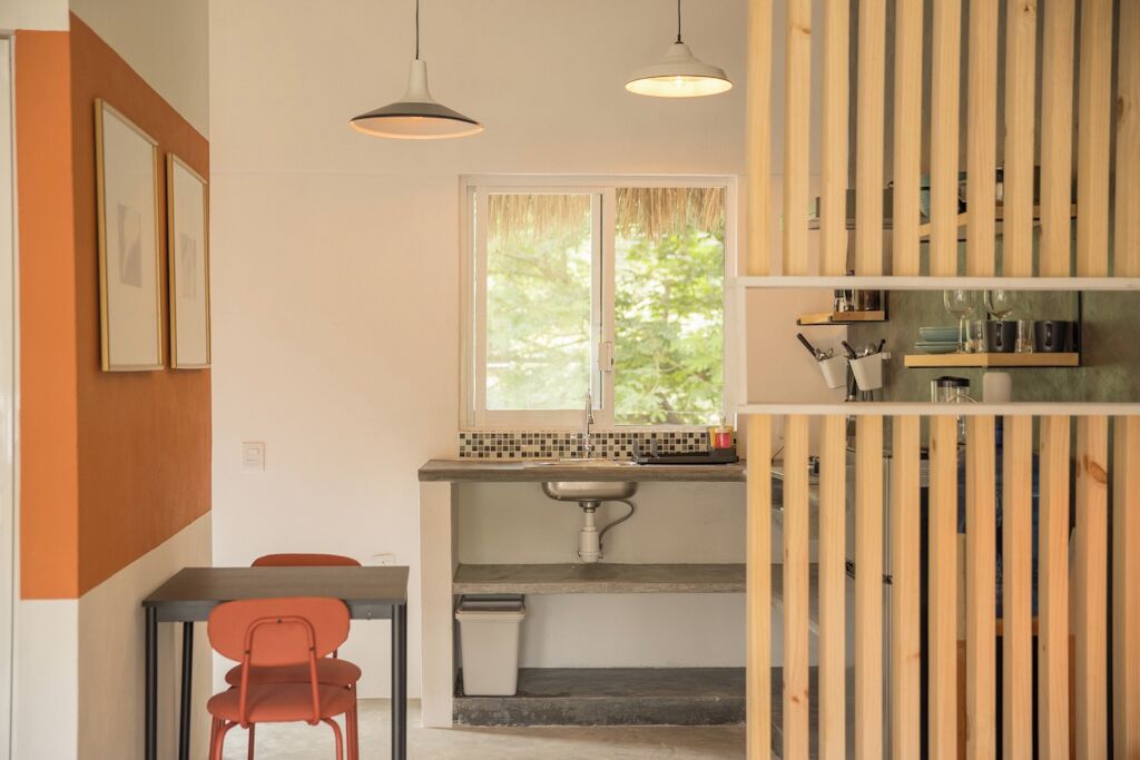 A compact kitchen with a window, a sink, and a dining area with chairs.