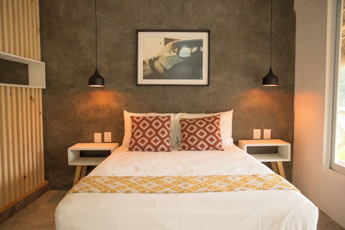 A neatly arranged bedroom with a large bed, two bedside tables, and a framed picture on the wall.