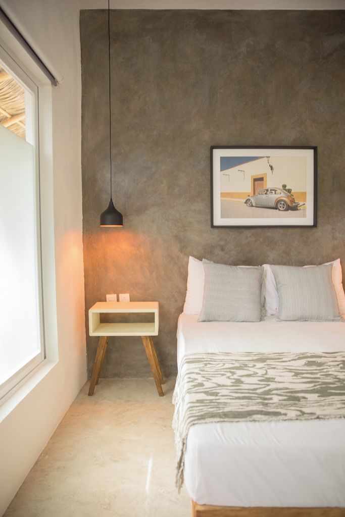 Ein Schlafzimmer mit Bett, Nachttisch, Hängeleuchte und einem gerahmten Bild an der Wand.