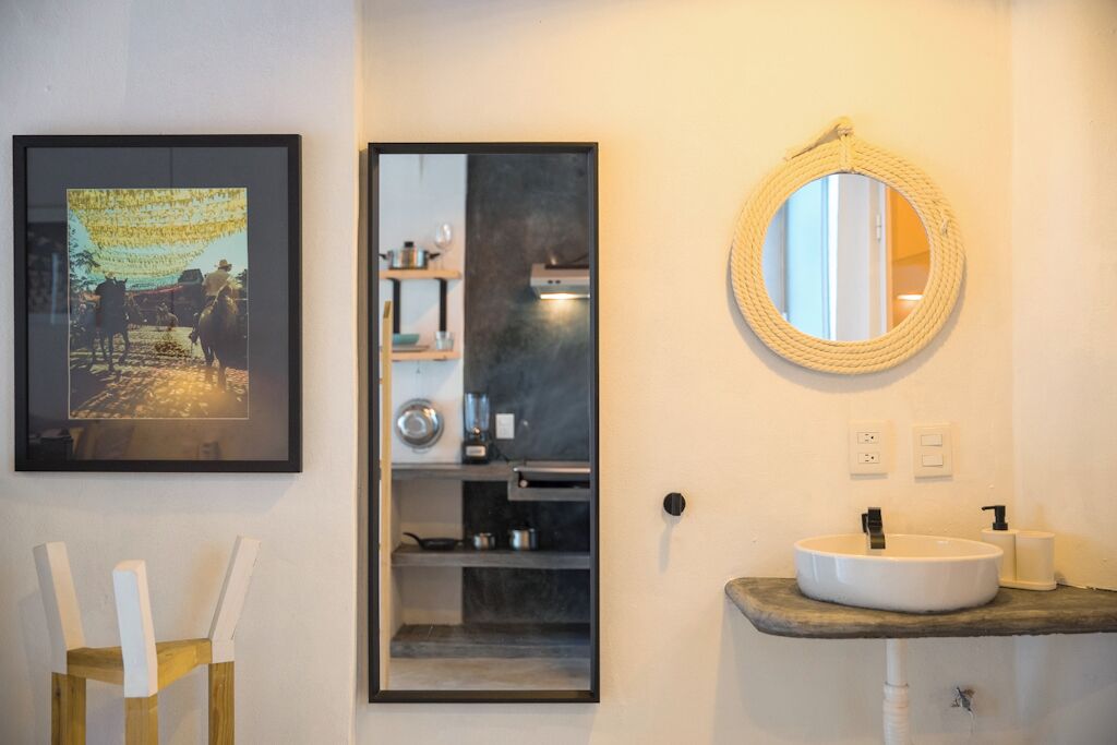 A bathroom with a framed photograph, a mirror, and a sink.