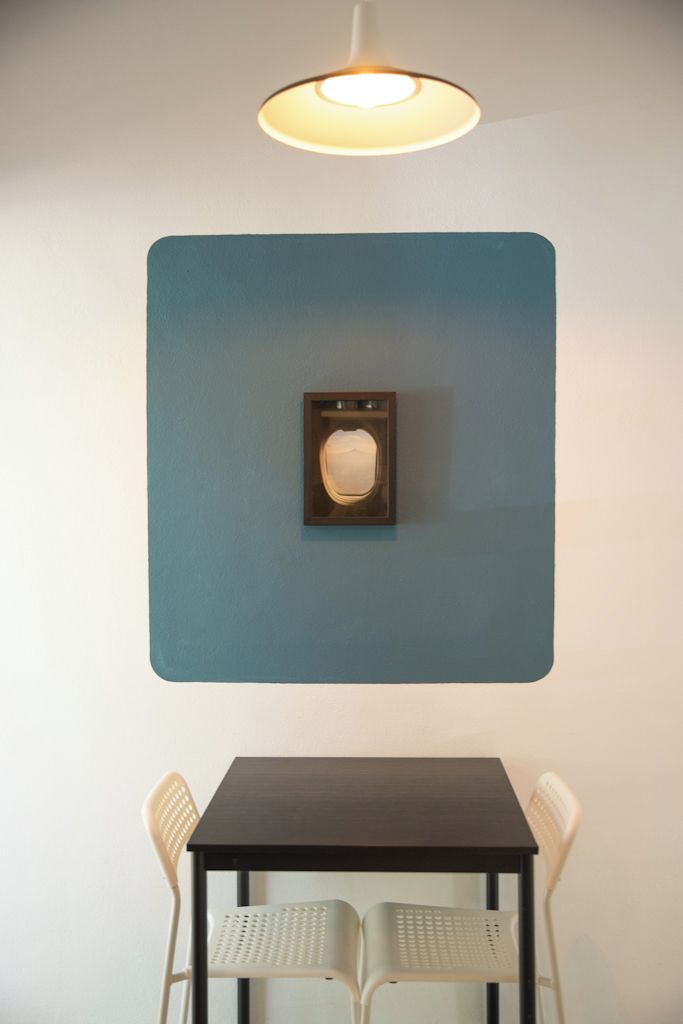 A room with a dark wooden table and two white chairs, a blue accent wall, and a wall-mounted light fixture.