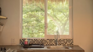 Uma cozinha com janela, pia e painel de azulejos.