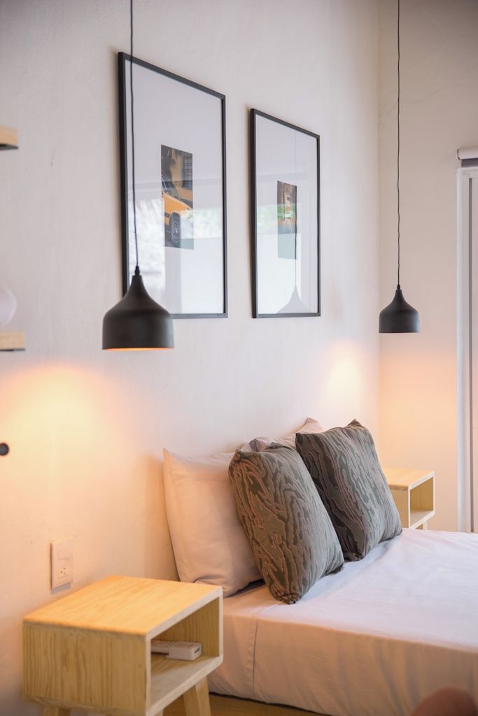 A modern bedroom with a bed, two bedside tables, and two pendant lights.