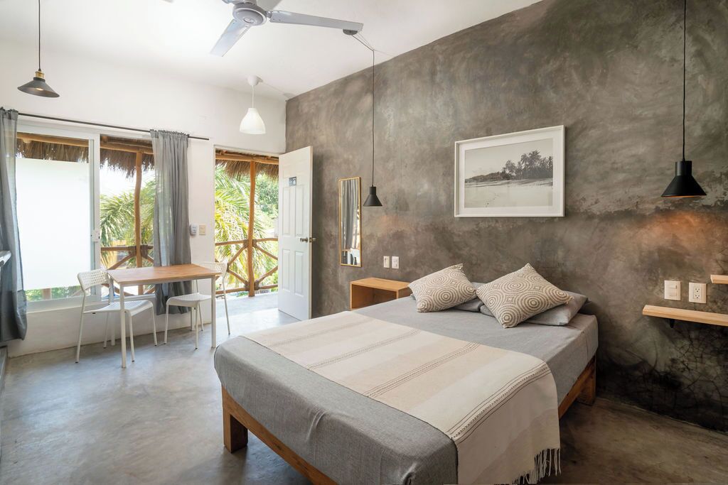 Un dormitorio con cama, mesitas de noche, escritorio y sillas.