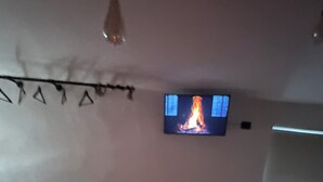 Een hotelkamer met een bed, een aan de muur bevestigde televisie en een klein tafeltje met een stoel.