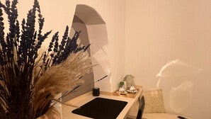 Een eetgedeelte met een houten tafel, een witte stoel, een zwarte placemat en een vaas met gedroogde planten.