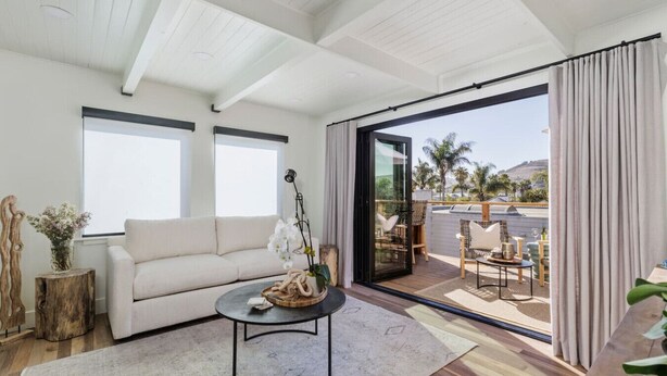 A modern living room with a sofa, coffee table, and a view of the outdoors through large sliding glass doors. - The Coral House — Modern Luxury 1BR with Ocean View Balcony | Cal King Bed + Queen Sleeper, Sleeps 4 · Folding Glass Balcony Doors · Full Kitchen · AC · Two Exclusive Beach Cruisers · Avila Beach · Managed by Solmaré Stays (Avila Beach)